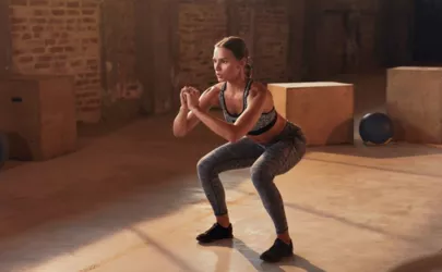 Frau macht Squat oder Kniebeuge im Fitnessstudio