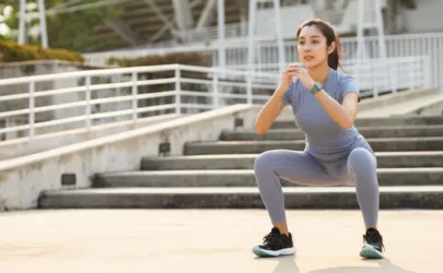 Frau macht Squat als Voraktivierung zum Laufen