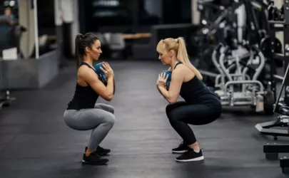 Zwei Frauen trainieren mit Kettlebells während ihres Trainings in einem Fitnessstudio