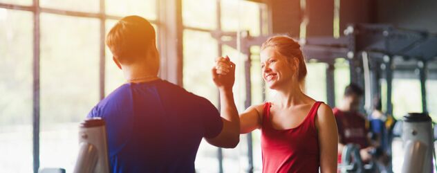 Ein junger Mann klatscht mit einer jungen Frau in einem Fitnessstudio ab.